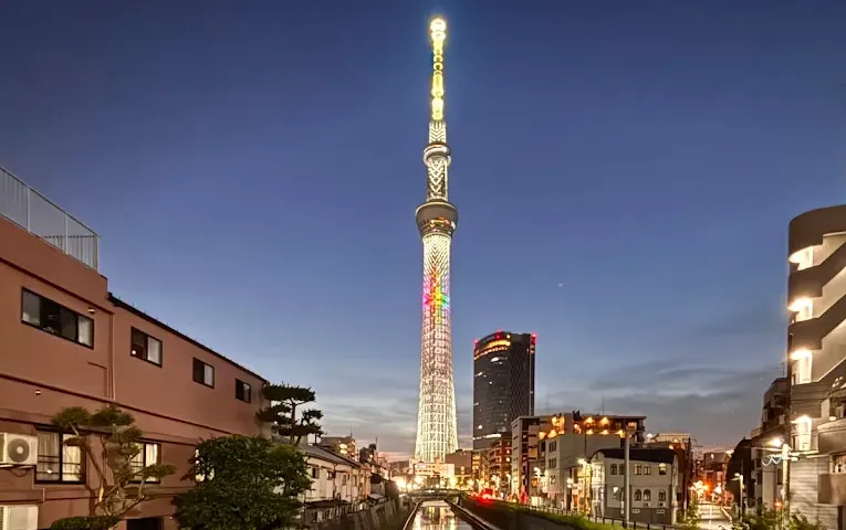 夕暮れ時、街並みの中にそびえ立つ東京スカイツリー。